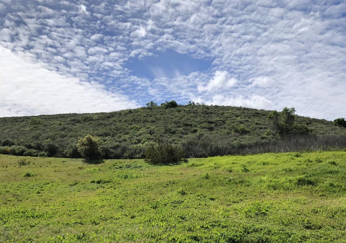 Clouds over a grassy hill